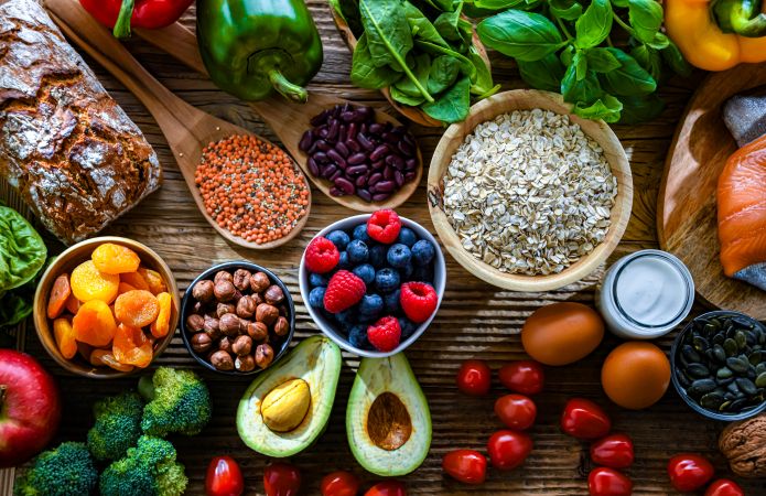Flat lay of diverse food raw materials including fresh vegetables, grains, berries, and nuts for food industry trends.