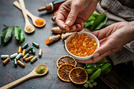 A person holding a bowl of gel capsules alongside natural food ingredients, supporting nutraceutical innovation.