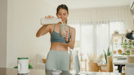 Woman in athletic wear pouring a protein shake for a lactase-supported sports nutrition drink.