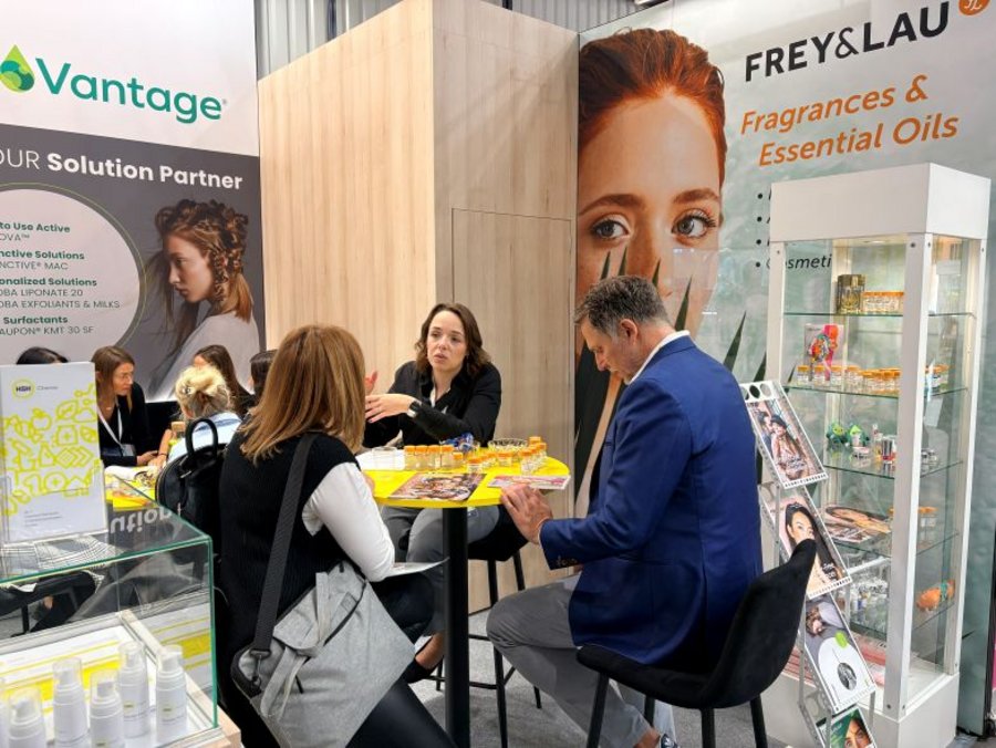 Visitors meet at a table with fragrance samples in front of the FREY&LAU display at the HSH Chemie booth, HPCI 2026.