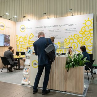 Visitors at HSH Chemie’s booth with personal care ingredient displays and yellow graphics at PCI Days 2026.