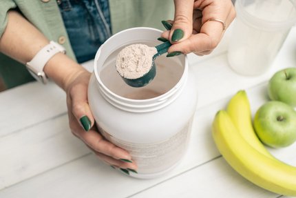 Person scooping pure protein powder into a container, representing food raw material trends and health management in 2026.