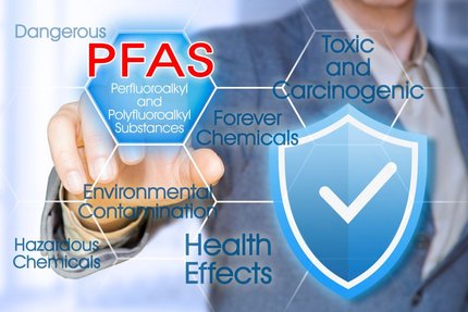 Person in business attire points to a PFAS graphic warning of toxicity, health effects and environmental contamination.
