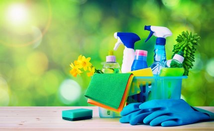 Eco-friendly cleaning caddy with spray bottles, scrub brush, sponge, gloves, and flowers.